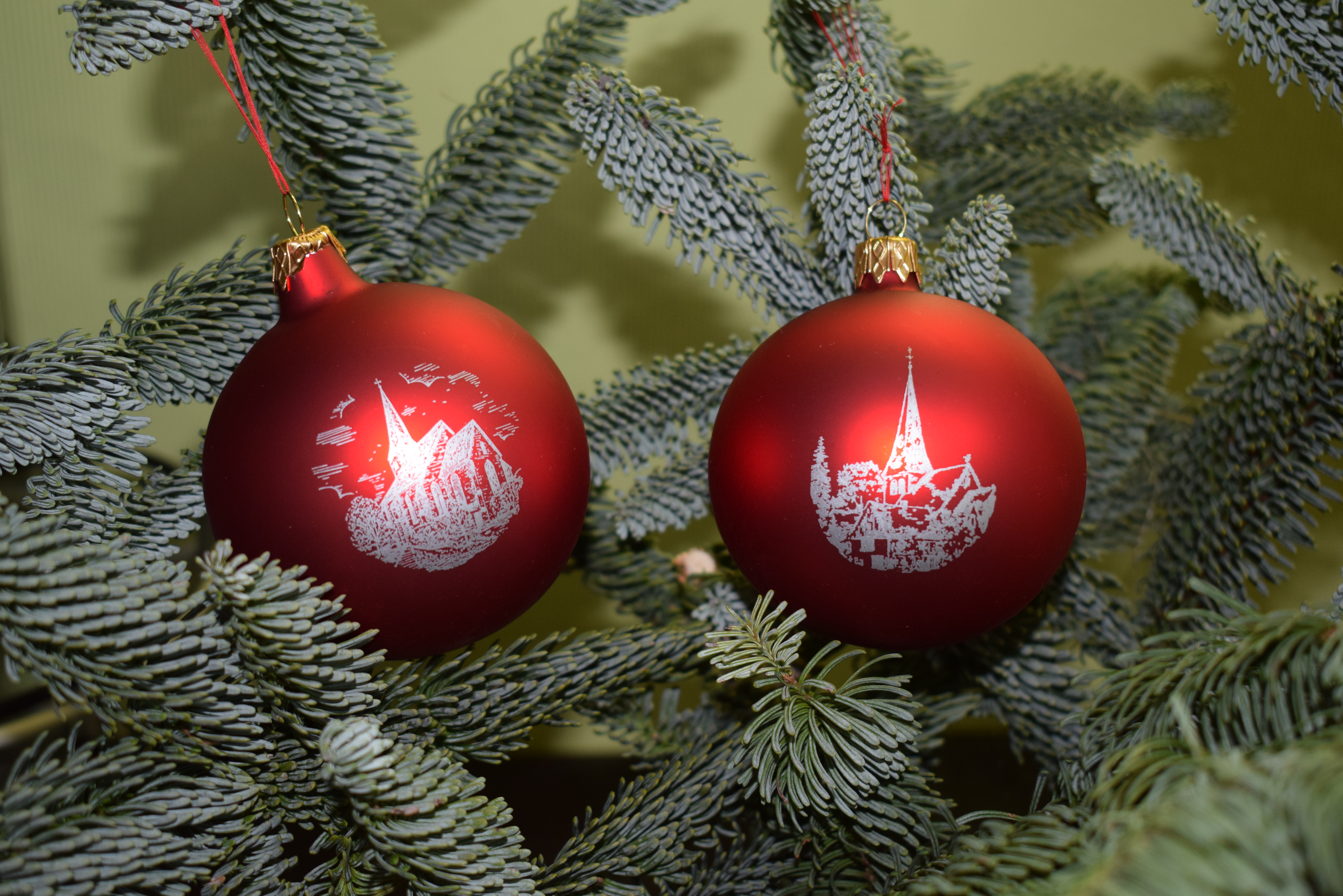 Rote Weihnachtsbaumkugeln mit Emblemen unserer beiden Kirchen